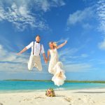 Hochzeit am Strand - Ehepaar spring vor Freude